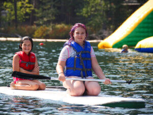 Two girls kneel on a paddleboard