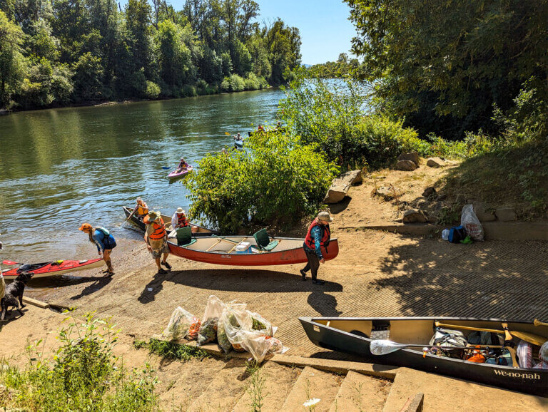 Pulling watercraft from the river after a weed harvesting event.